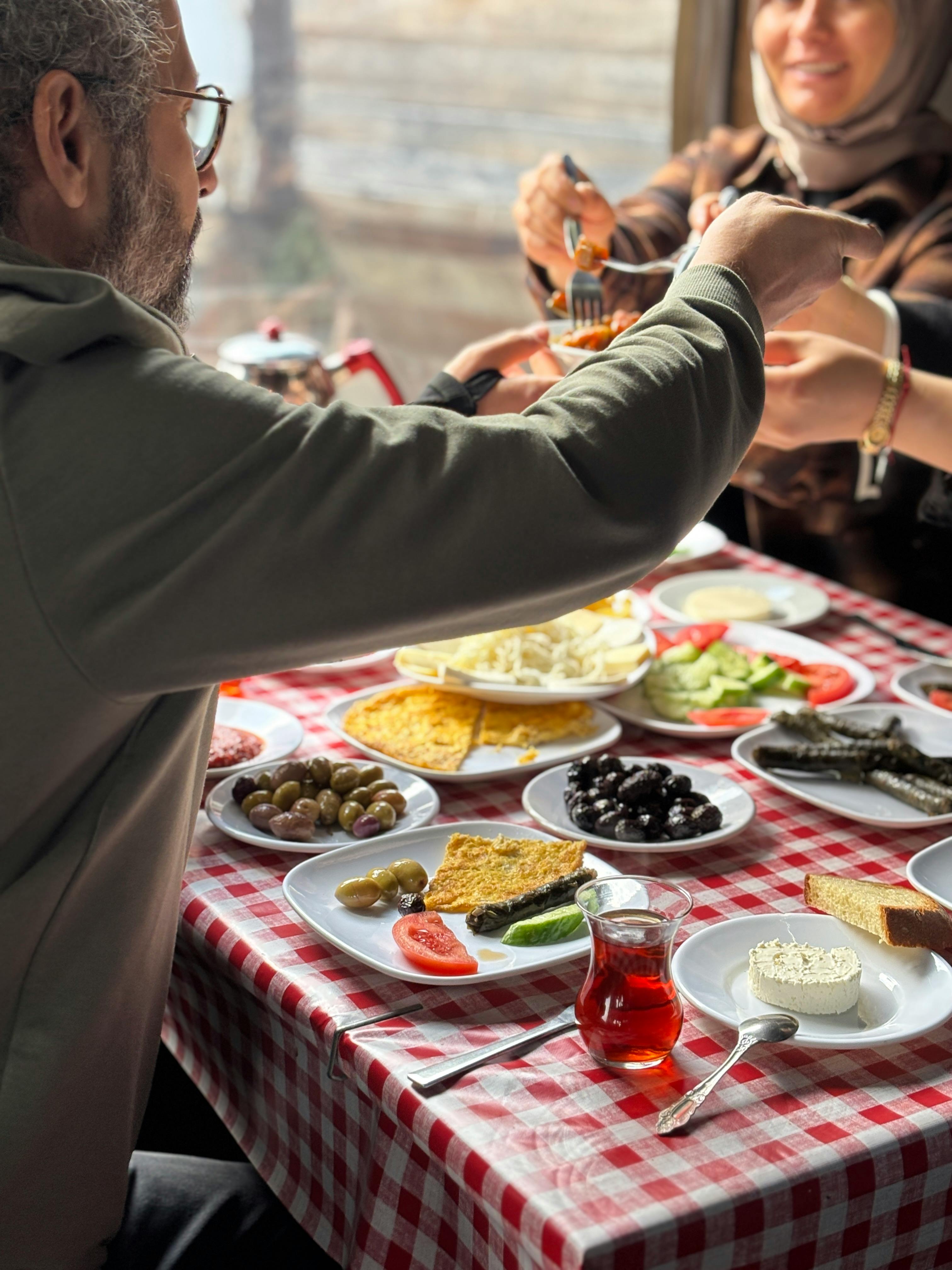 A traditional breakfast spread on a checkered table enjoyed by people indoors.